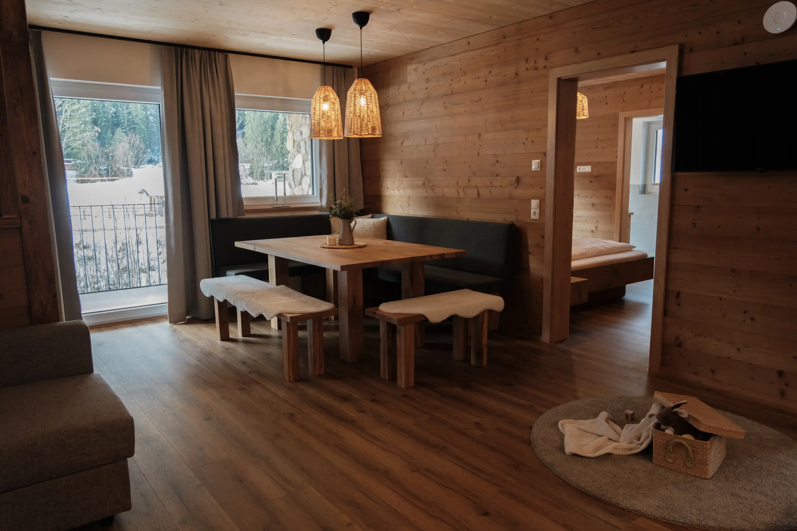 Gemütliches Esszimmer im Chalet-Stil mit Holzwänden und Blick auf die verschneite Landschaft.