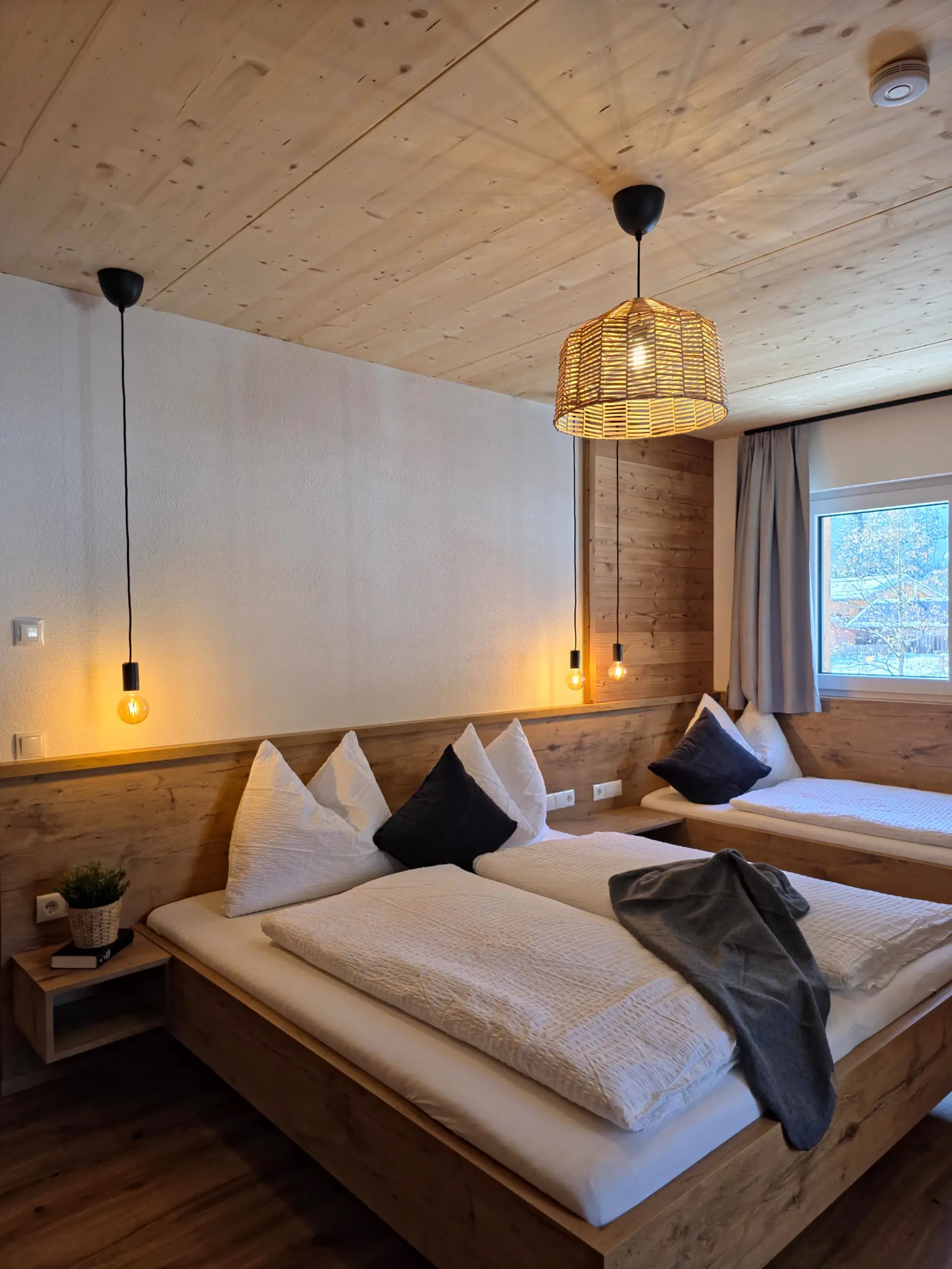 Gemütliches Hotelzimmer mit Holzbalkendecke und zwei Betten. Helle, einladende Atmosphäre.