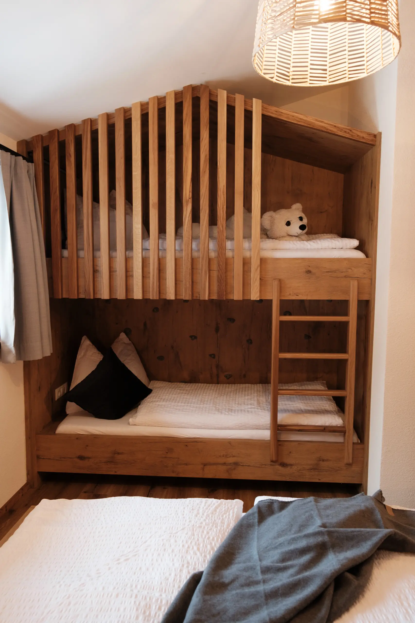 Gemütliches Holzbett im Zimmer mit Etagenbett und Teddybär.