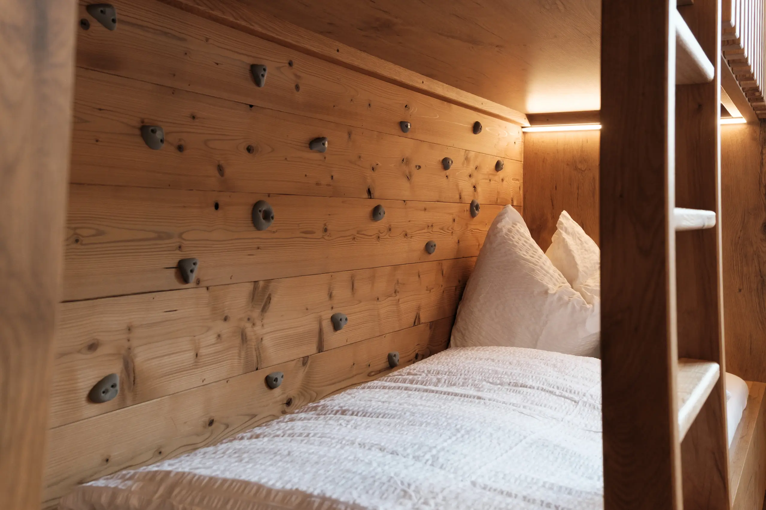 Holzbett mit Kletterwand und weißer Bettwäsche. Gemütliches Zimmerdesign.