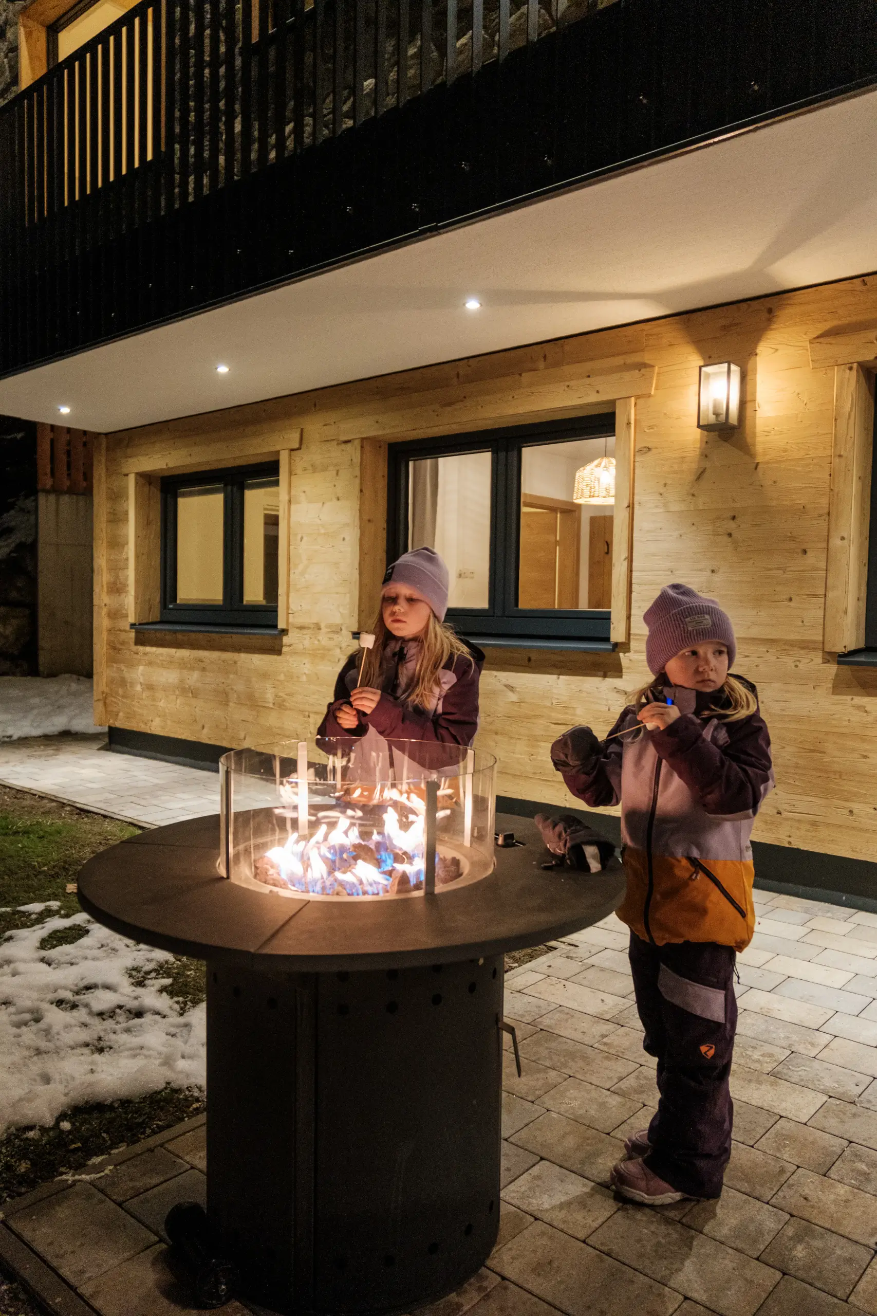 Zwei Mädchen rösten Marshmallows über einem Feuer im Freien.