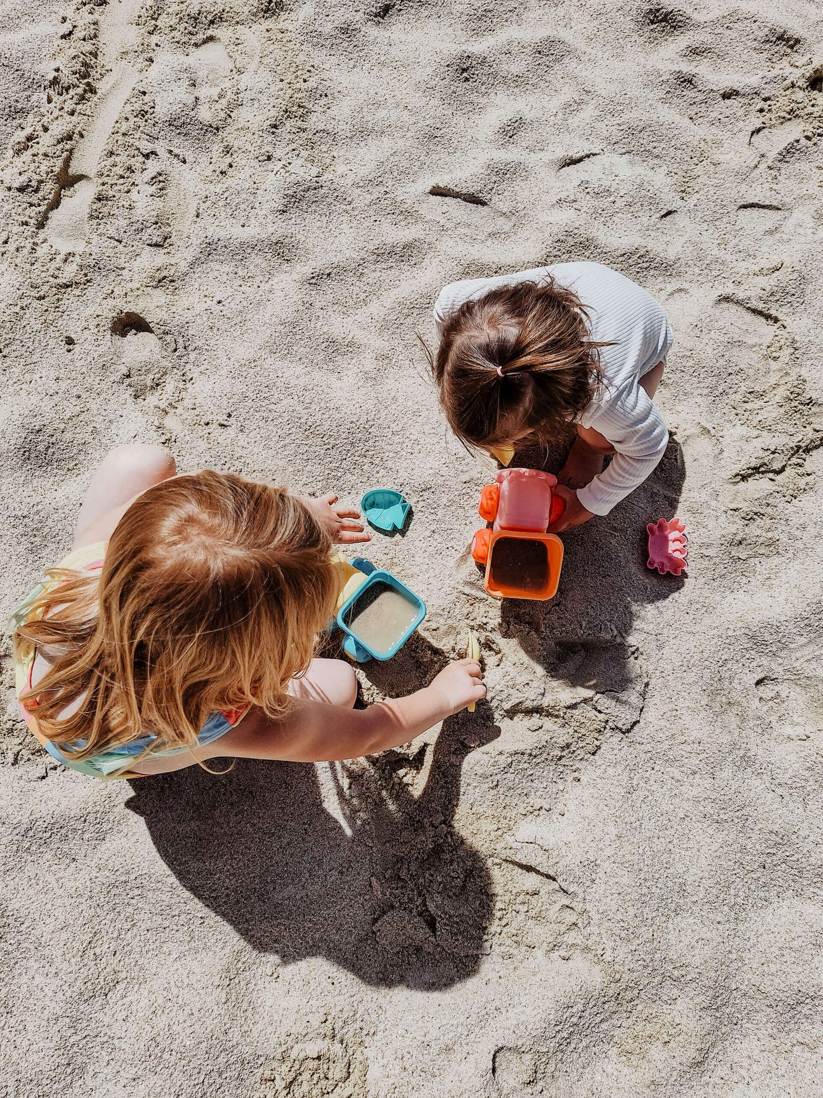 Zwei kleine Mädchen spielen mit Sandspielzeug am Strand
