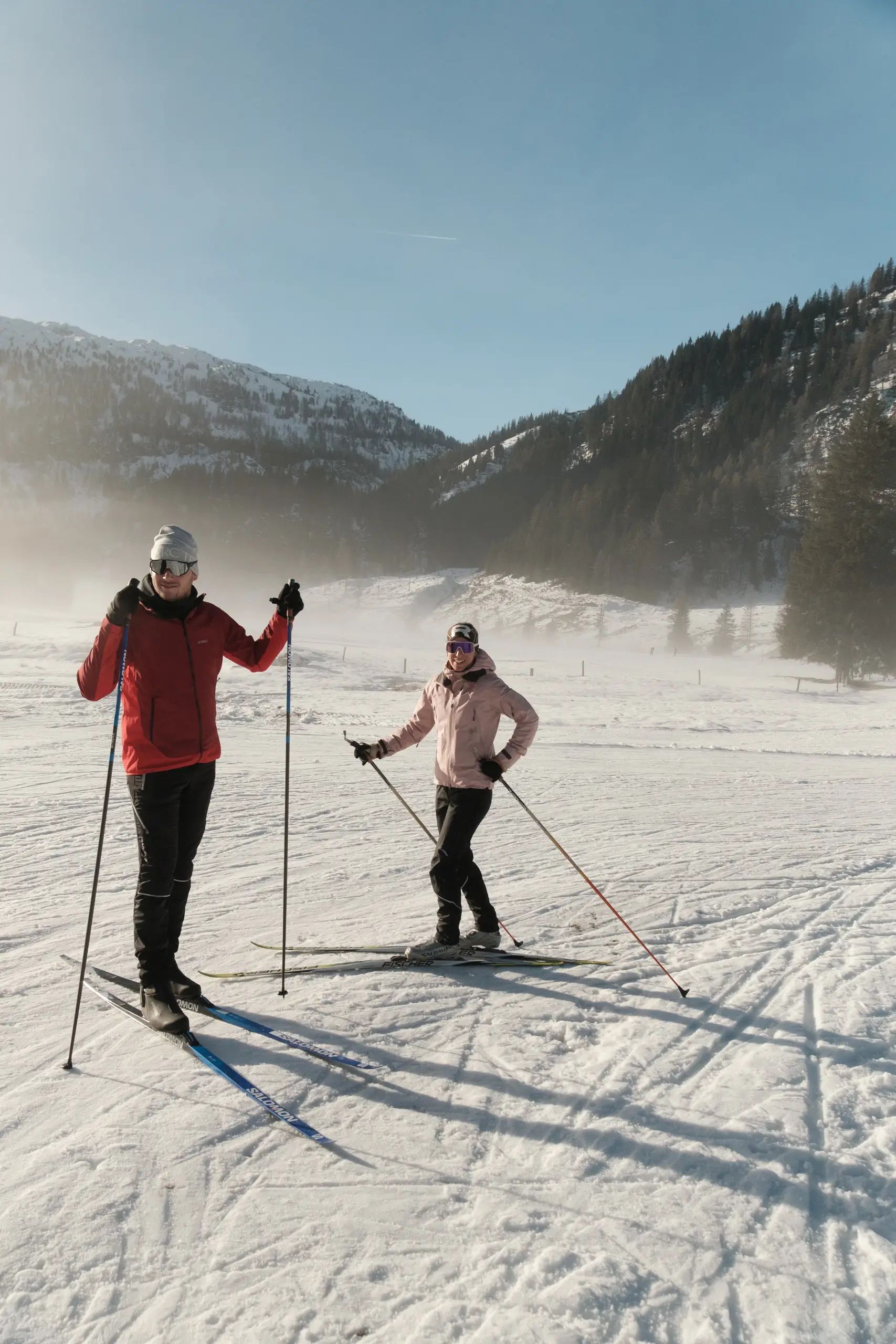 Zwei Personen beim Skilanglauf in verschneiter Berglandschaft.