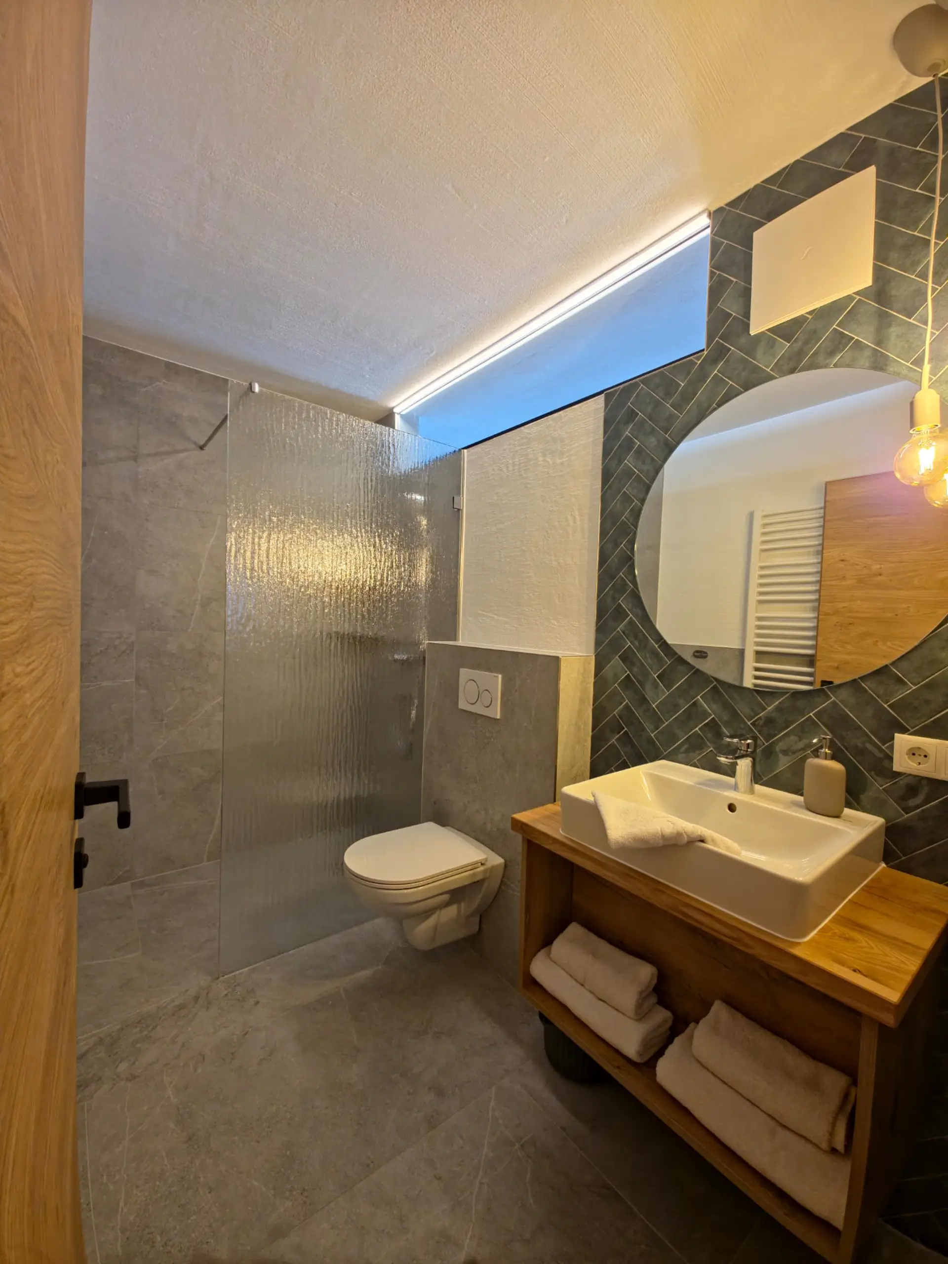 Modernes Badezimmer mit Dusche, WC und Holzwaschtisch.