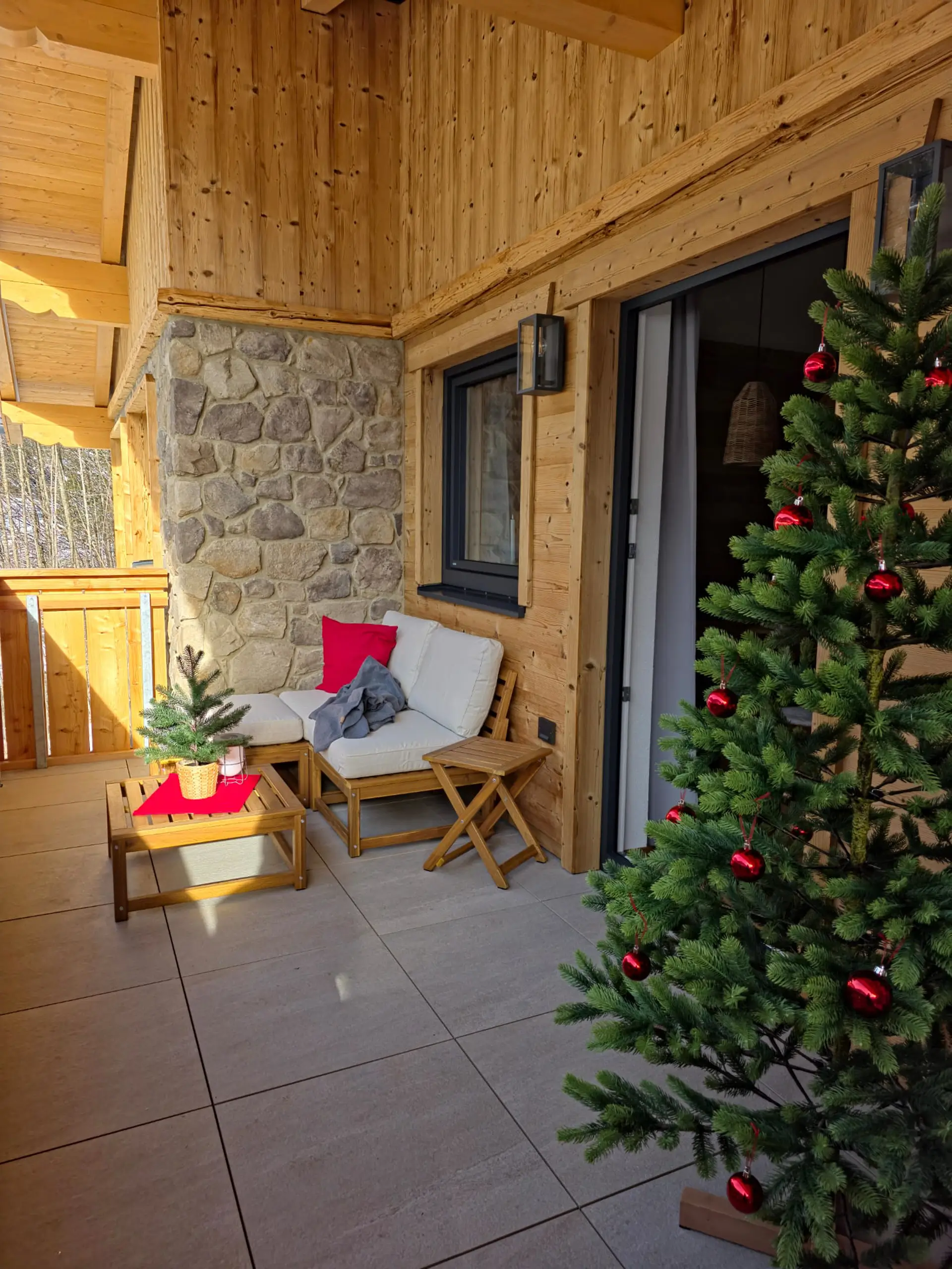 Gemütliche Terrasse im Chalet-Stil mit Weihnachtsdeko, Sofa und Holzelementen.